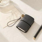 Dear Folio Mini Wrap Charm Notebook styled on warm ivory linen with a pen.