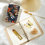 Embroidered Floral Wrap Notebook styled in a warm reading and writing setting